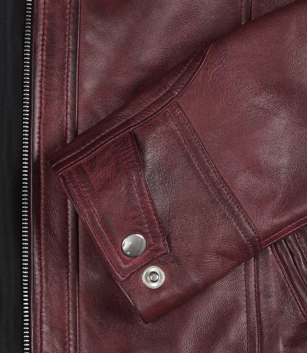 Close-up of a maroon leather jacket with buttons and zipper details.